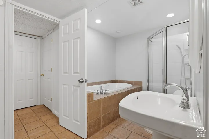 Pedestal sink with chrome faucet, walk-in shower with glass enclosure, built-in bathtub, and ceramic tile flooring