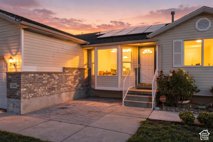 Solar panels, light-toned siding, brick exterior accent, bay window, and a front entry with handrails