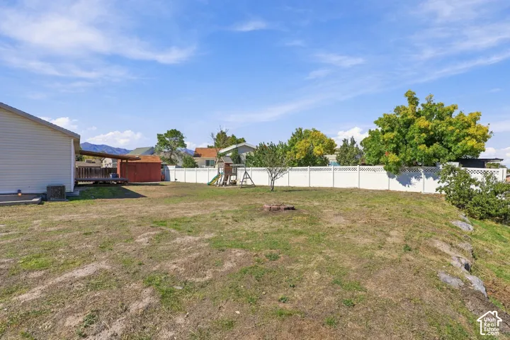 Expansive property featuring a white privacy fence, an elevated wooden deck, and a red storage shed