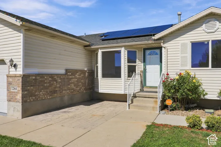 Solar panel array, neutral-toned siding, brick wainscoting, integrated garage, and a welcoming entry porch