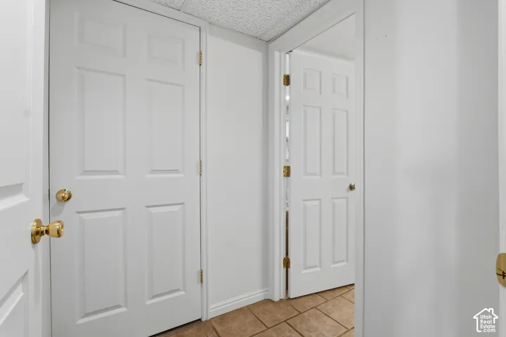 White six-panel interior doors with brass hardware, neutral wall paint, and tiled flooring
