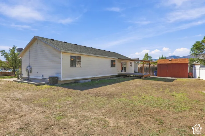 Expansive backyard featuring a wood deck, red storage shed, and white vinyl siding