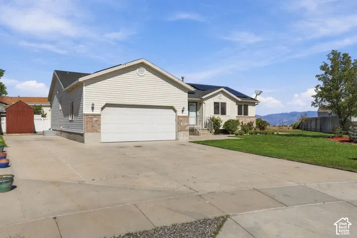 Light-colored siding exterior with brick accents, attached garage, concrete driveway, and a manicured lawn