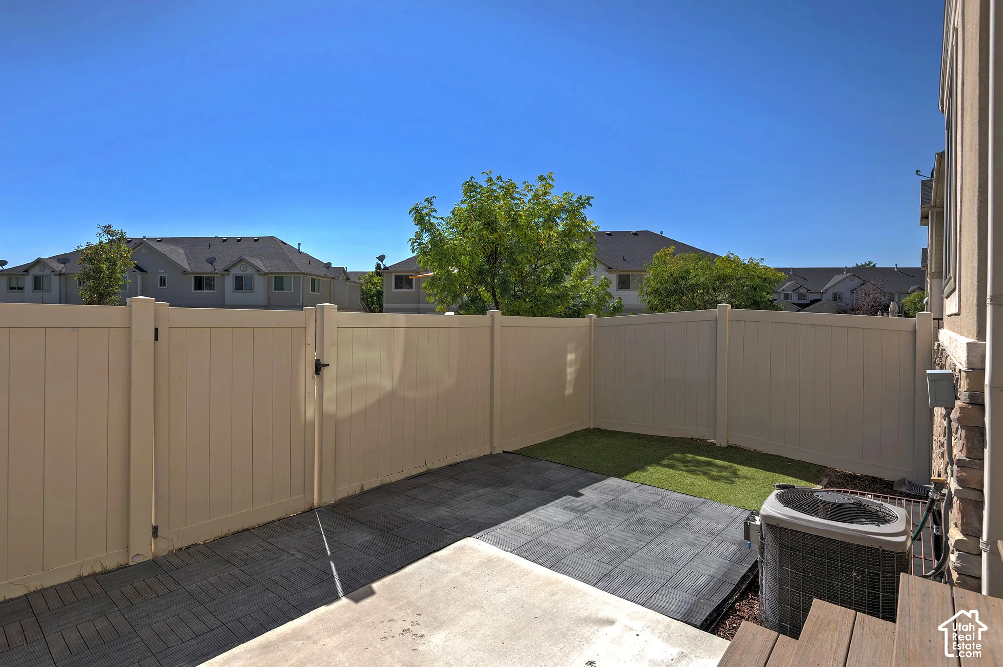 Private fenced patio area featuring a concrete slab, artificial turf, and composite decking
