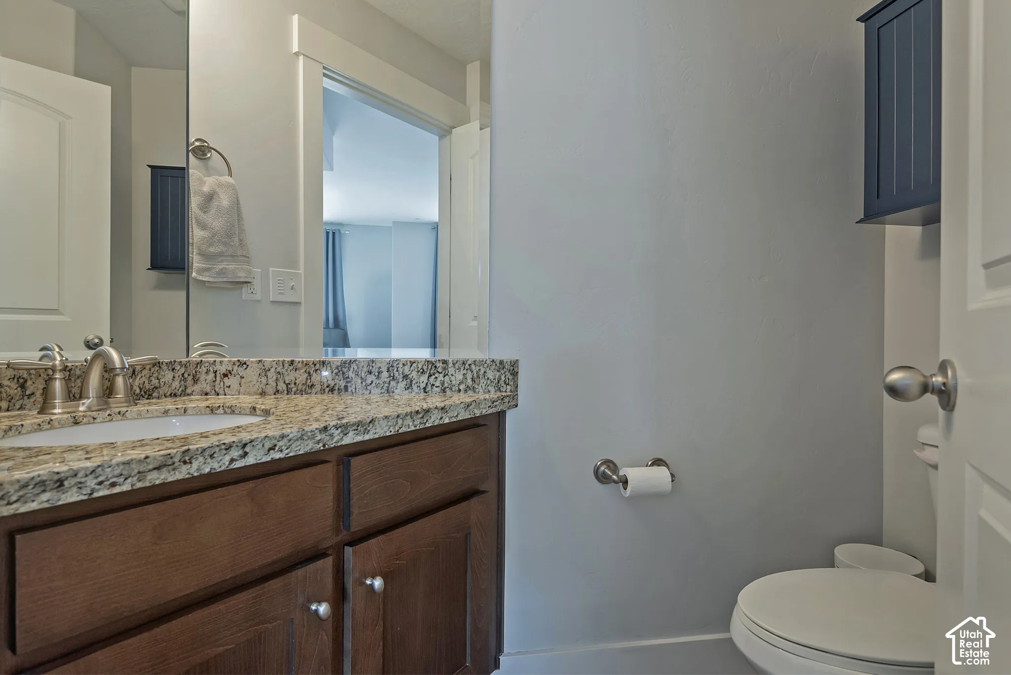 Vanity with wood-finish cabinetry, countertop with integrated sink, and wall-mounted mirror