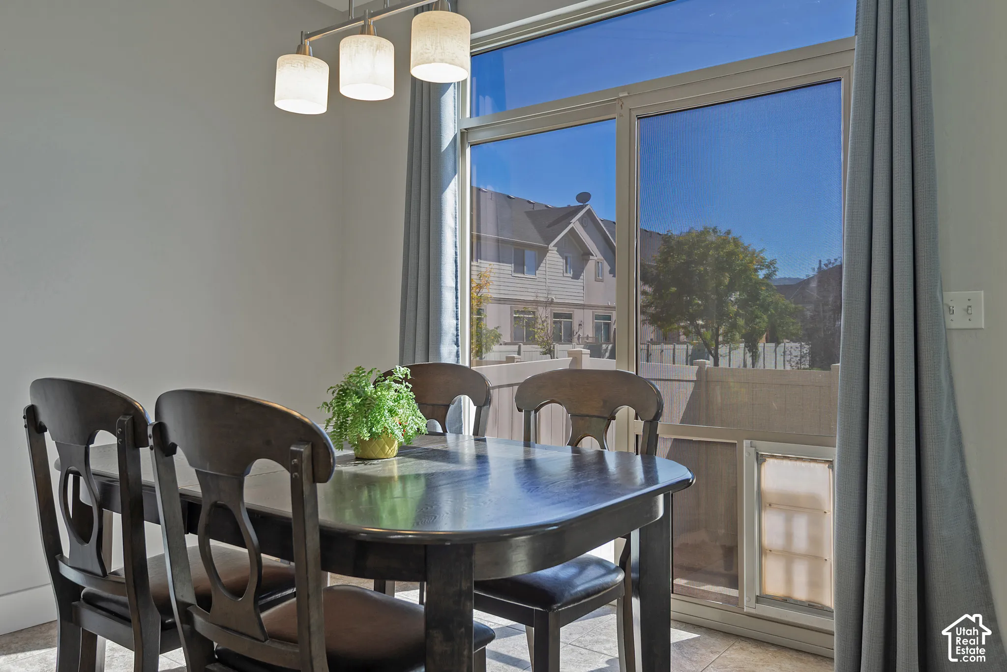 Sliding glass door, tiled flooring, overhead light fixture, light gray walls, white baseboards