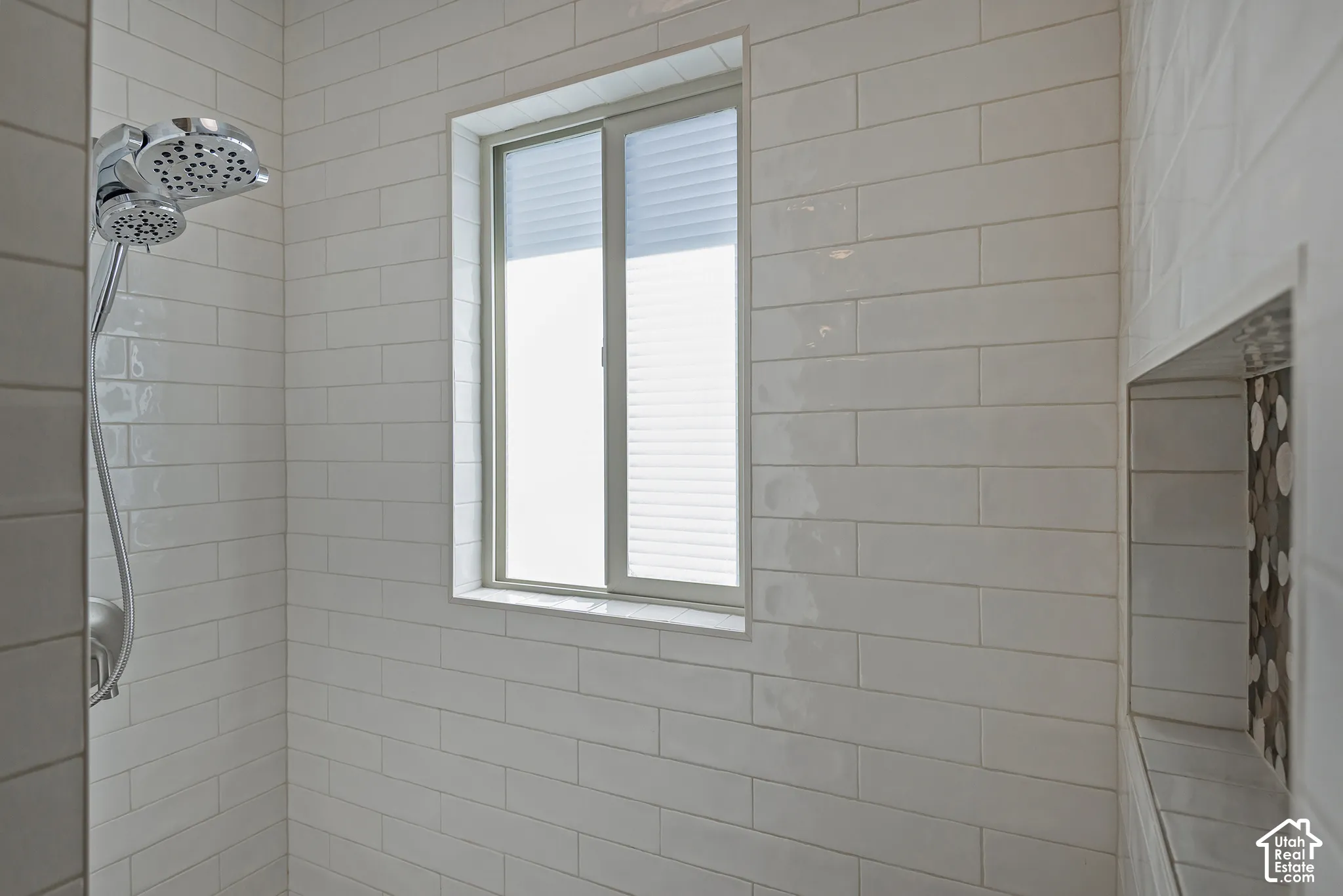 White subway tile shower enclosure with a built-in niche featuring mosaic tile