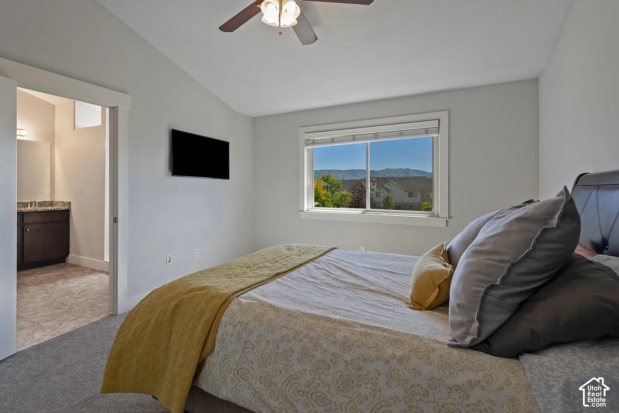 Carpeted bedroom with a vaulted ceiling, a ceiling fan, and a prominent window