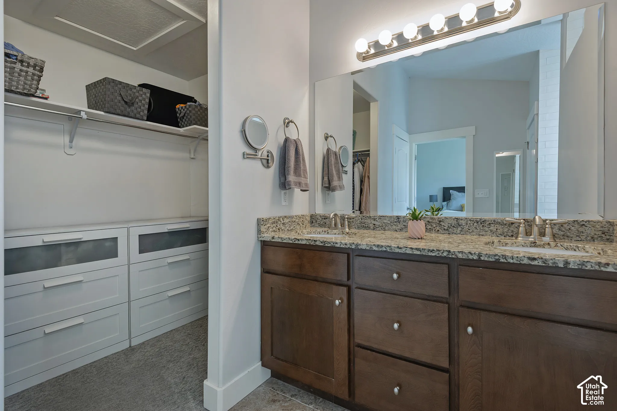 Dual vanity with granite countertop and integrated sinks, complemented by a large wall-mounted mirror and overhead lighting