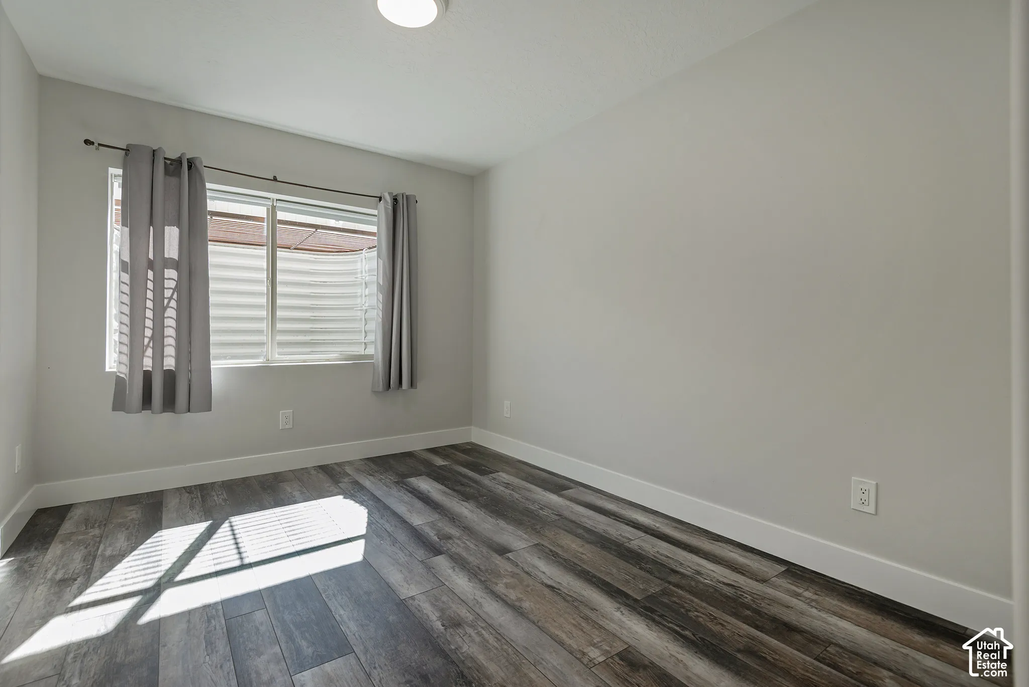 Wood-finish flooring, white walls, and a window with blinds