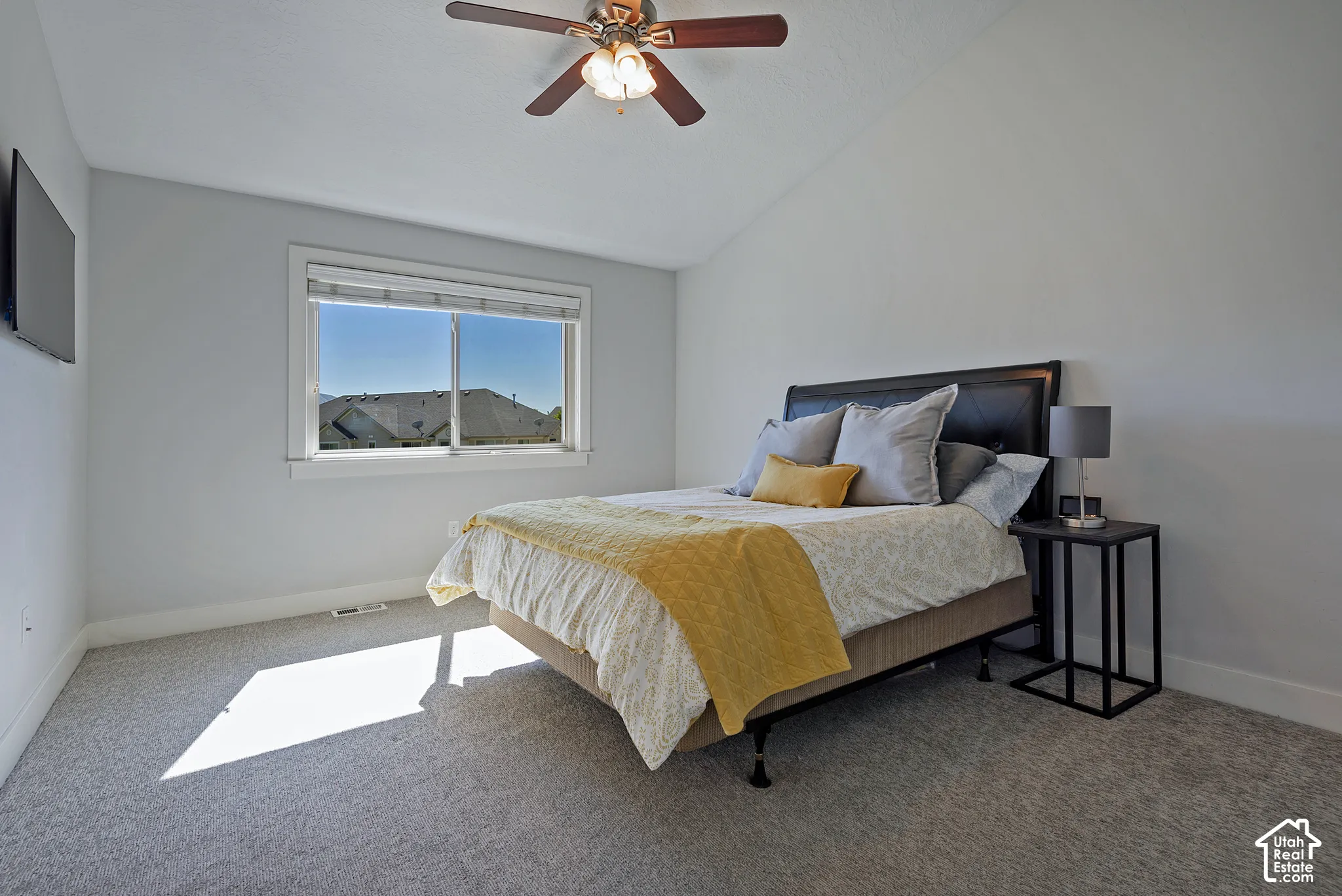 Vaulted ceiling with an attached ceiling fan, large window, and carpeted flooring