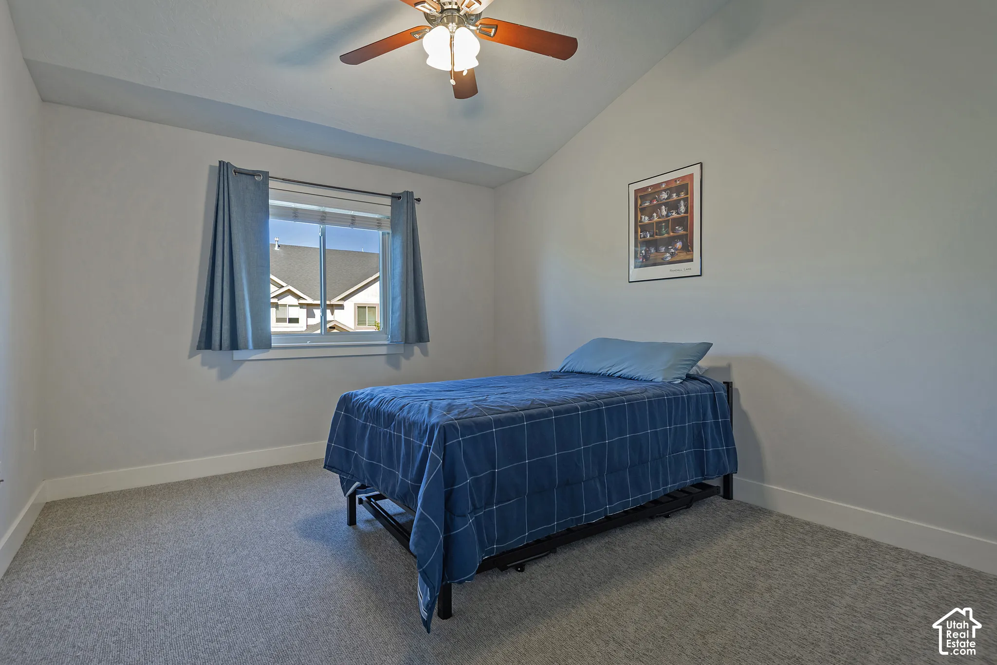 Vaulted ceiling with a ceiling fan, carpeted flooring, and a window with a curtain rod