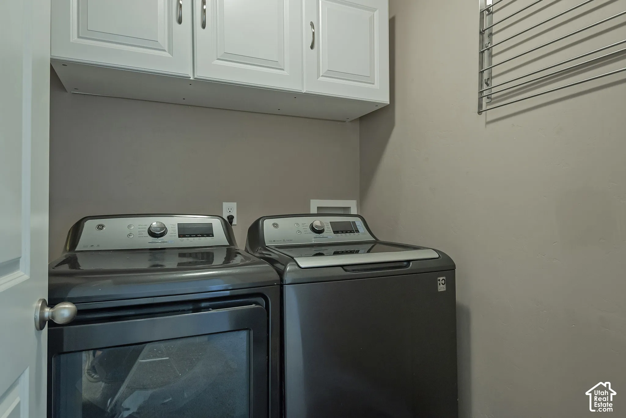 Upper white cabinetry, wall-mounted drying rack, and neutral wall paint