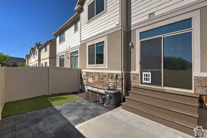 Private fenced patio featuring artificial turf and modular paver flooring