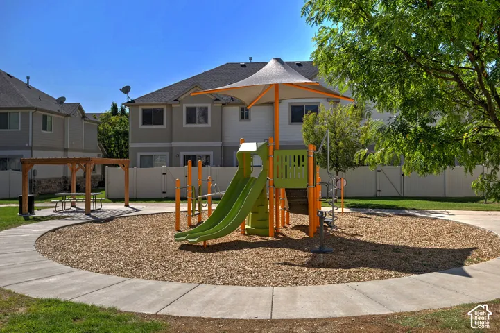 Outdoor play structure with dual slides, shaded by a fabric canopy
