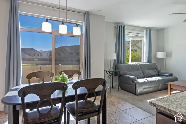 Sliding glass door, pendant lighting, tile flooring, carpeted area, and a large window