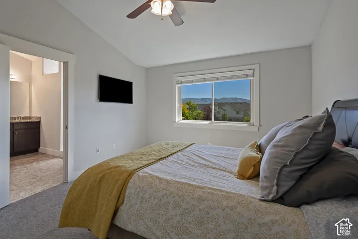 Carpeted bedroom with a vaulted ceiling, a ceiling fan, and a prominent window