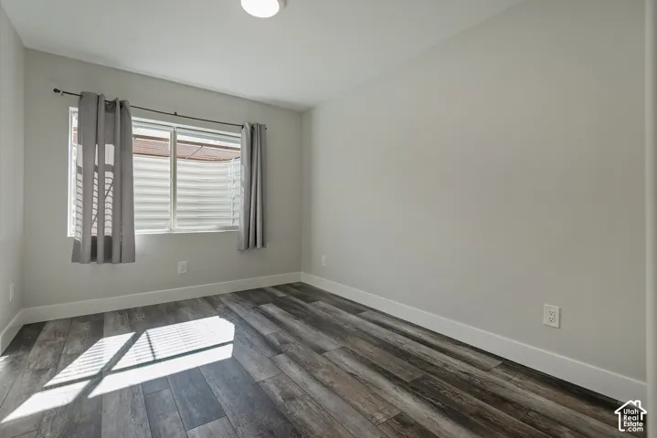 Wood-finish flooring, white walls, and a window with blinds
