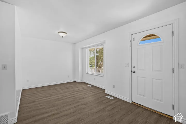 Entryway featuring a white door with an arched transom, wood-finish flooring, a flush-mount light fixture, and a window with white trim