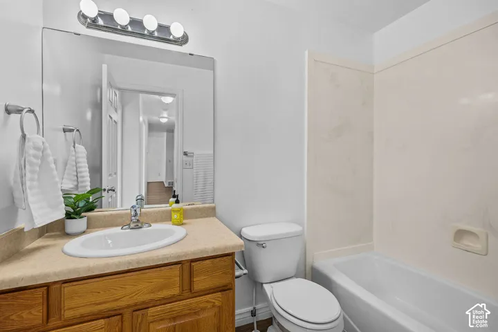 Bathroom featuring a wood-finish vanity with an integrated sink, a light-toned countertop, and an overhead vanity light