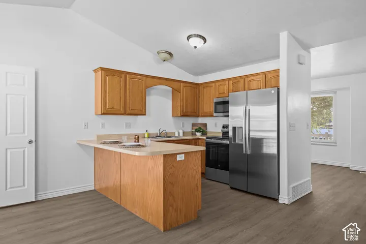 Kitchen featuring wood-finish cabinetry, stainless steel appliances, a breakfast bar, and wood-finish flooring