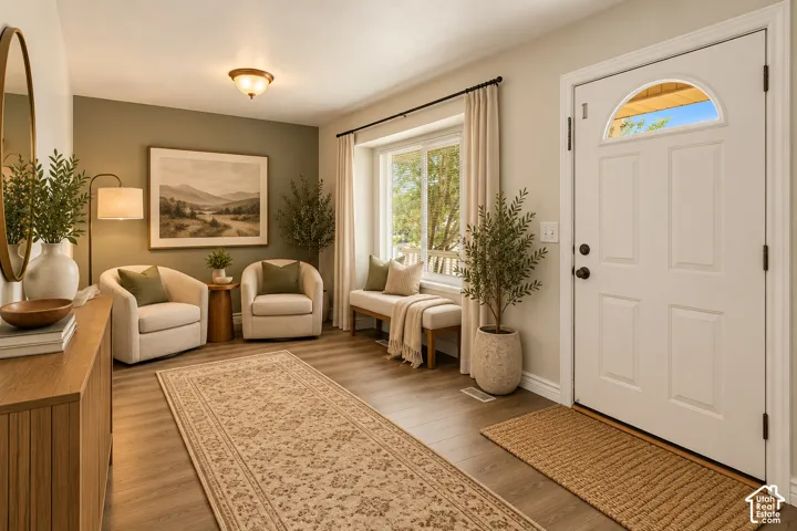 Entryway featuring wood-finish flooring, a white panel door with a semi-circular transom window, and a recessed window nook