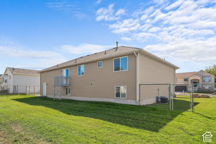 Expansive rear yard with green space, chain-link fencing, and a raised exterior deck