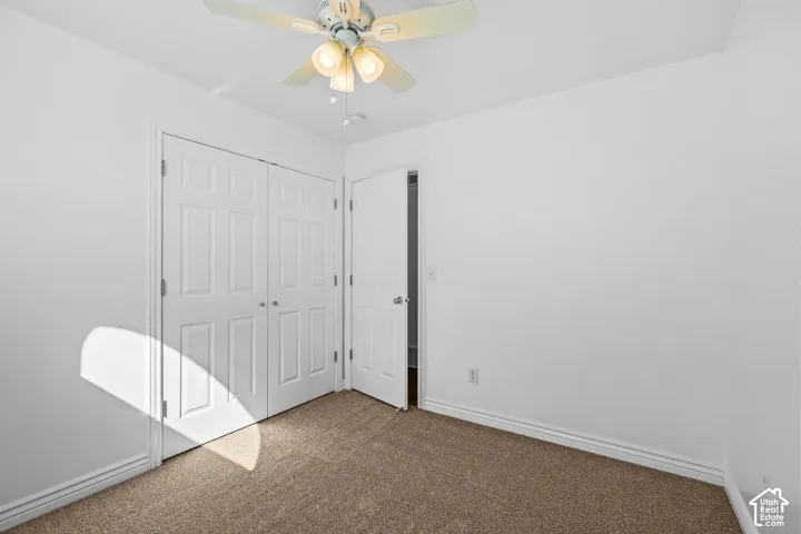 Light-colored carpeting, white walls, and a ceiling fan with integrated lighting