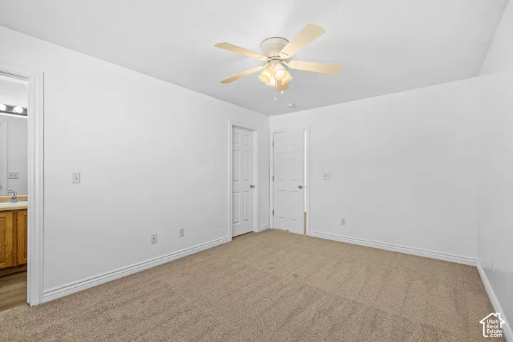 Neutral-toned carpeting, white walls, and a ceiling fan with integrated lighting