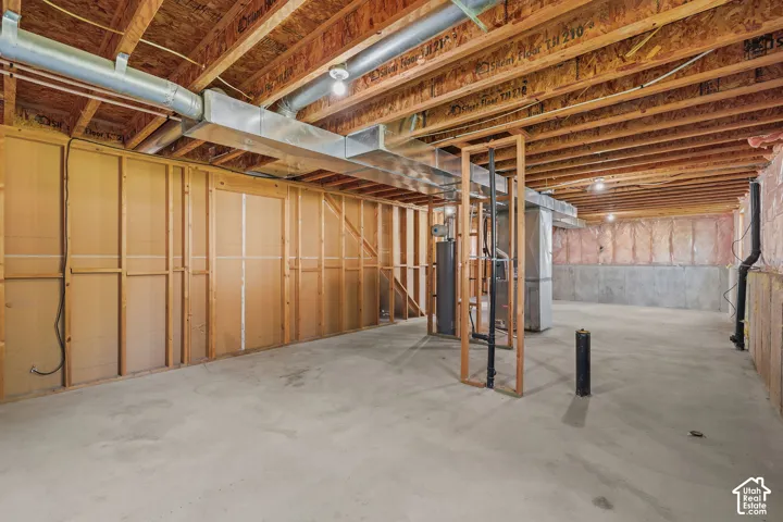 Unfinished basement with exposed ceiling joists, concrete flooring, and framed walls
