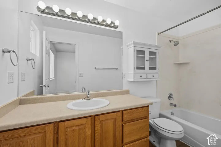 Vanity with wood-finish cabinetry, integrated sink, and laminate countertop