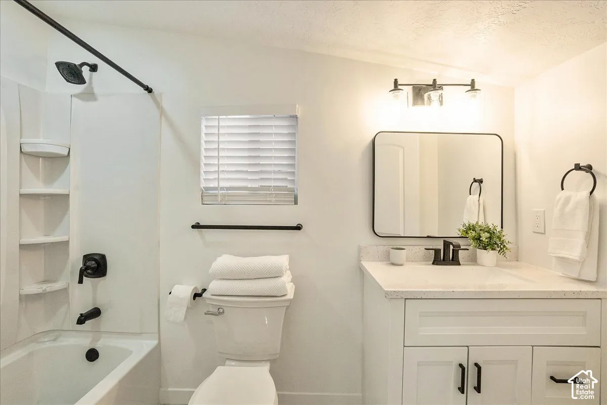 White vanity with a light-colored countertop, rectangular mirror, and matte black fixtures
