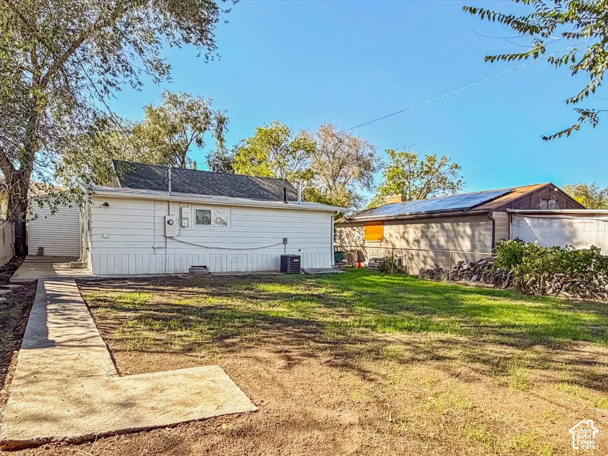 Expansive backyard with a concrete pathway and mature trees