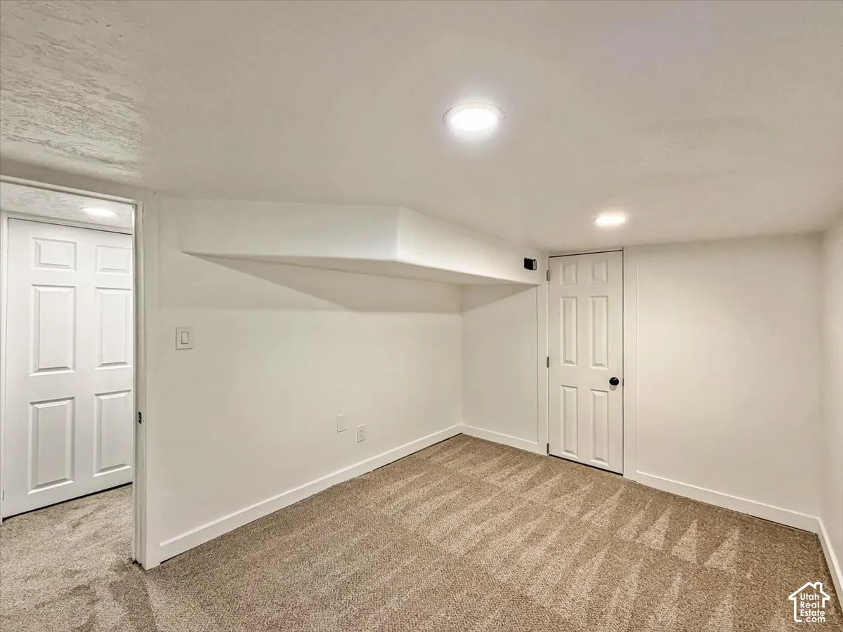 Recessed lighting illuminates the room, featuring a neutral carpet and white trim