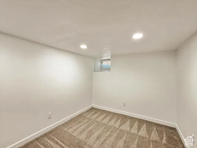 Recessed ceiling lighting, light-colored walls, patterned carpeting, and a small window