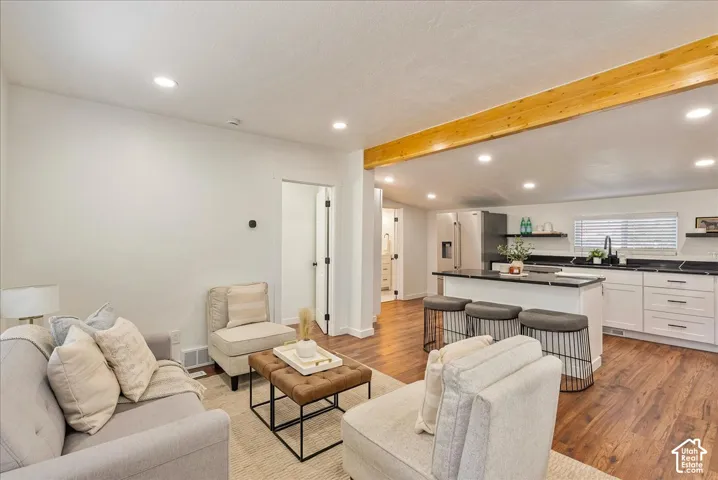 Open concept living area featuring wood-finish flooring, recessed lighting, and a prominent wood beam