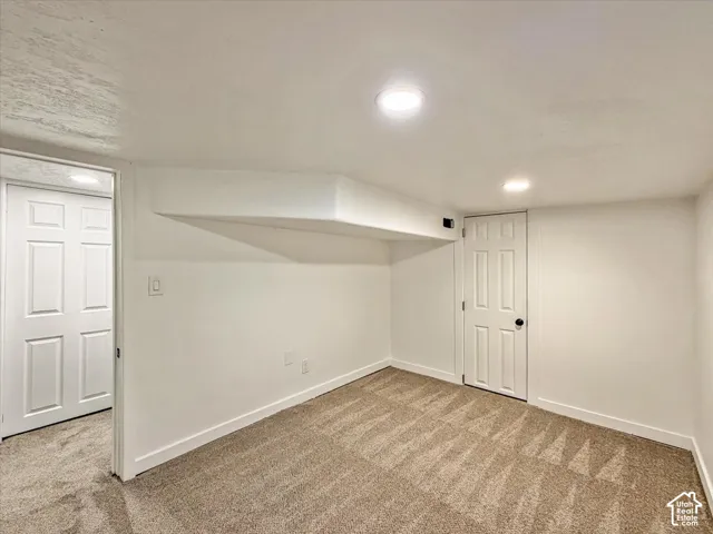 Recessed lighting illuminates the room, featuring a neutral carpet and white trim