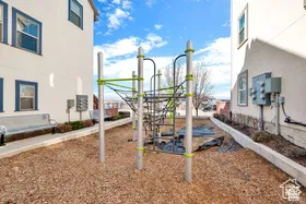 Recreational area featuring a modern climbing structure, wood chip ground cover, and adjacent seating