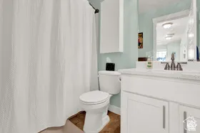 White vanity with a light-colored countertop, wall-mounted storage cabinet, and a framed mirror