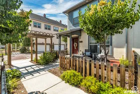 End unit Townhome in exstablished neighborhood. Exterior featuring a covered porch, wood-slat fencing, stone walkway, and a wooden pergola