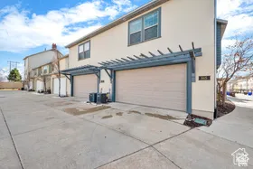 Stucco exterior with two garage doors and an overhead trellis