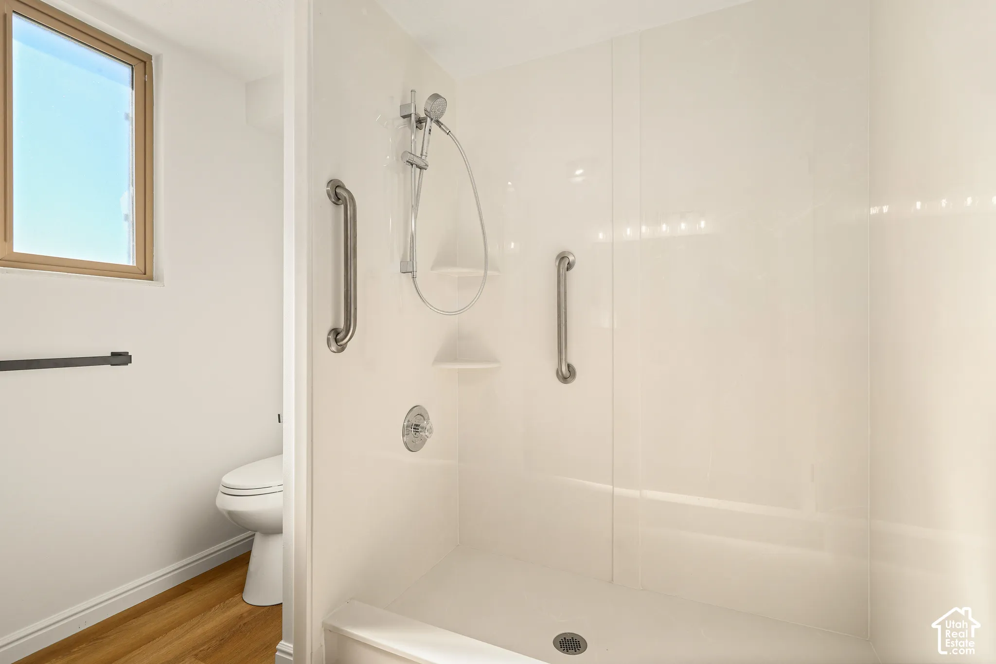 Walk-in shower with grab bars, handheld shower fixture, and built-in shelving