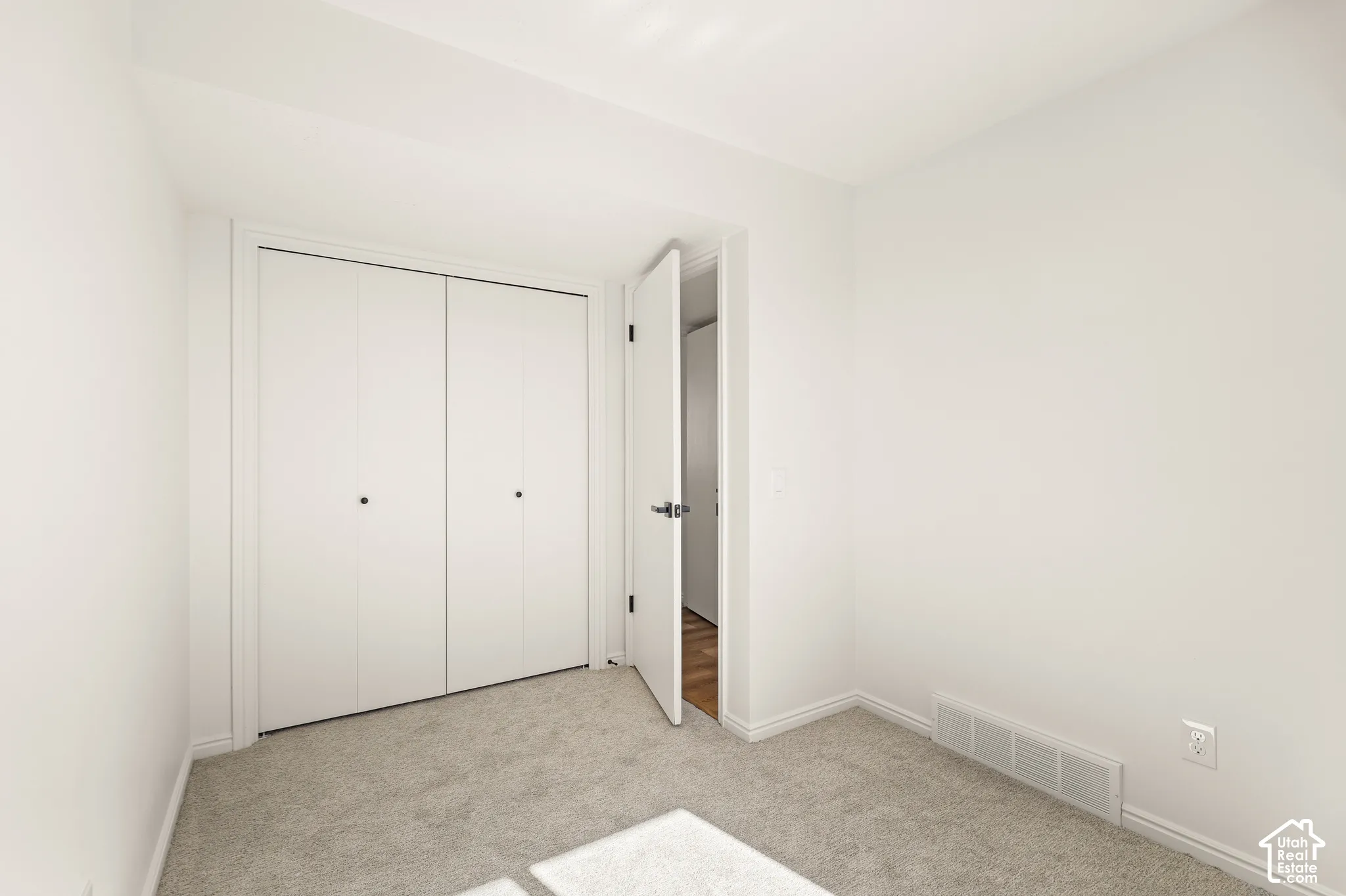 Neutral-toned carpeting, white walls, and a bi-fold closet door