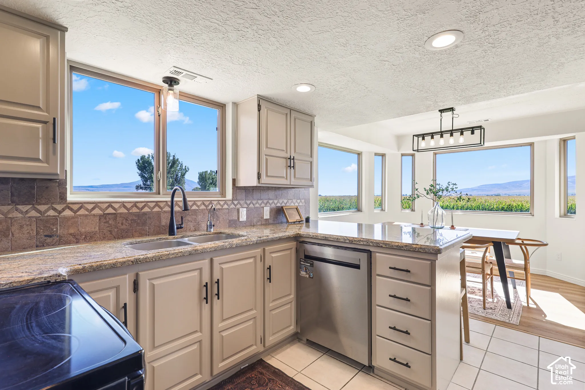 Kitchen featuring granite countertops, tile backsplash, built-in dishwasher, and ample cabinetry