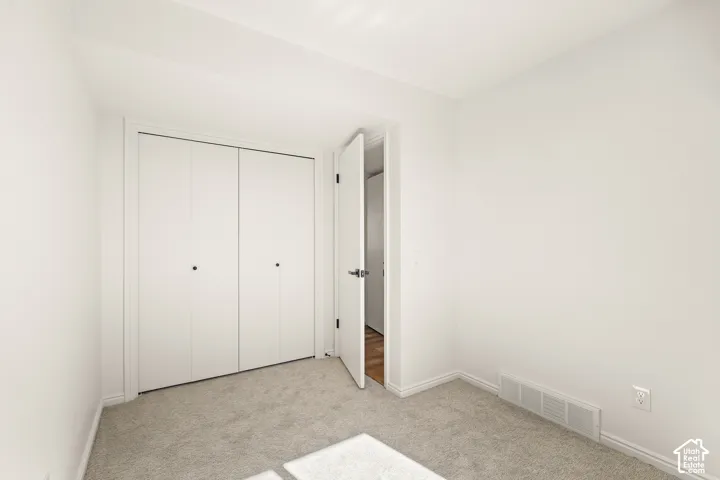Neutral-toned carpeting, white walls, and a bi-fold closet door
