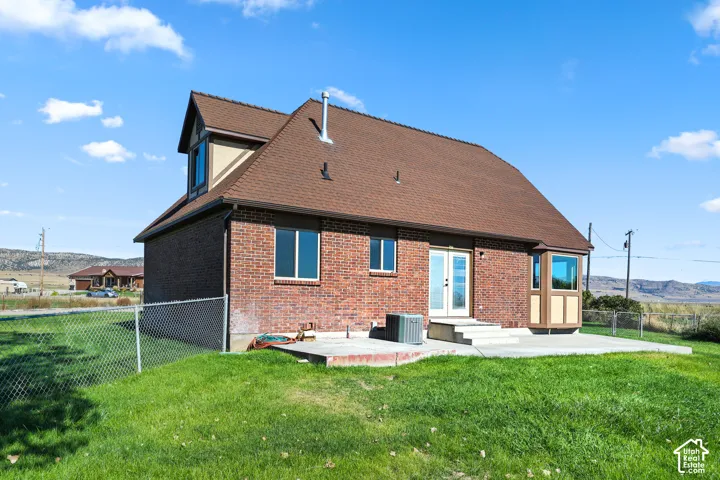 Brick exterior with dormer window, bay window, concrete patio, and fenced yard