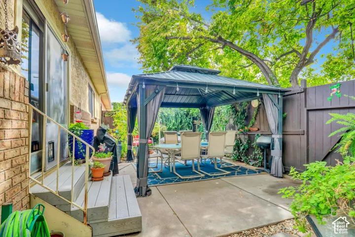 Patio area with a permanent gazebo structure, concrete hardscaping, and a privacy fence