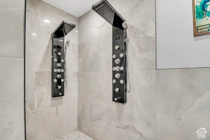 Spa-Inspired Shower Featuring Dual Black Body Jet Panels with Multiple Adjustable Nozzles, Rainfall Showerheads, and Sleek Tile Surround with Natural Stone-Look Finishes and Frameless Glass Enclosure
