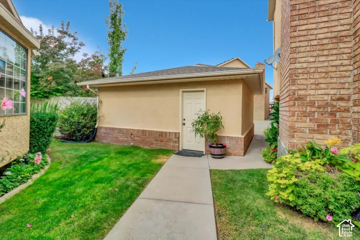Exterior featuring a stucco finish, brick accents, a gabled roof, and a concrete walkway