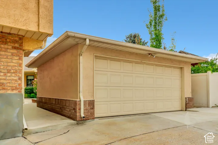 Attached garage with paneled doohttps://assets.utahrealestate.com/photos/280x210/hb5538457_84db5b80d3313a7c8ac5f714a0b561ca_6abde4e811e83.jpgr, stucco siding, and a brick veneer foundation
